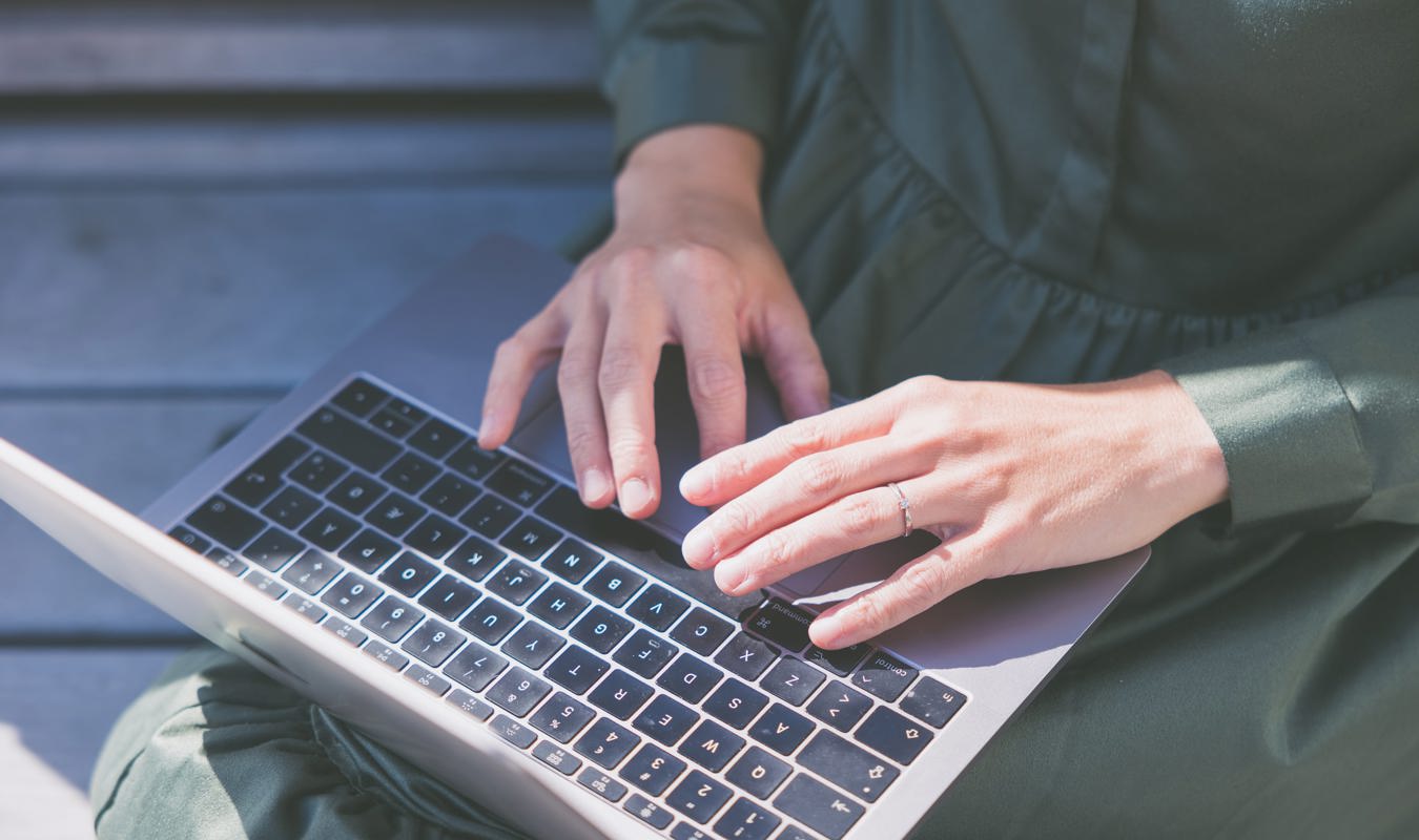 Kvinde der sidder og tager noter på sin computer, mens hun er ved at tage en online uddannelse