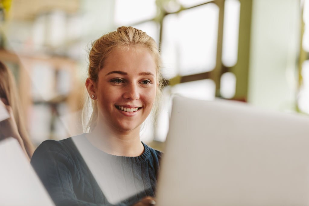 Glad kvinde der kigger på sin computer